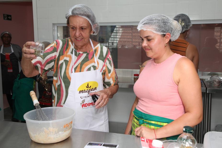 duas mulheres lado a lado preparam receita. #paratodosverem