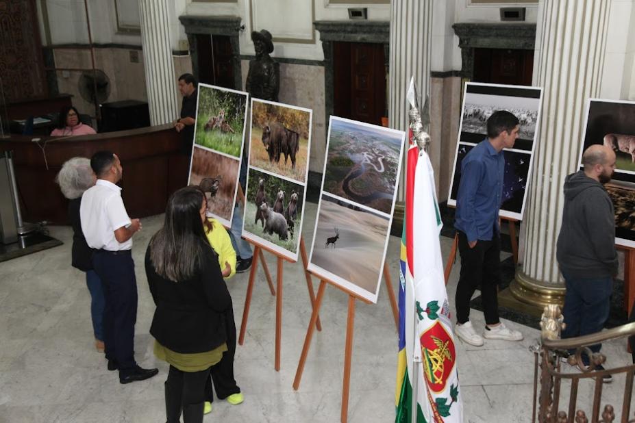 pessoas estão observando fotos em exposição. #paratodosverem