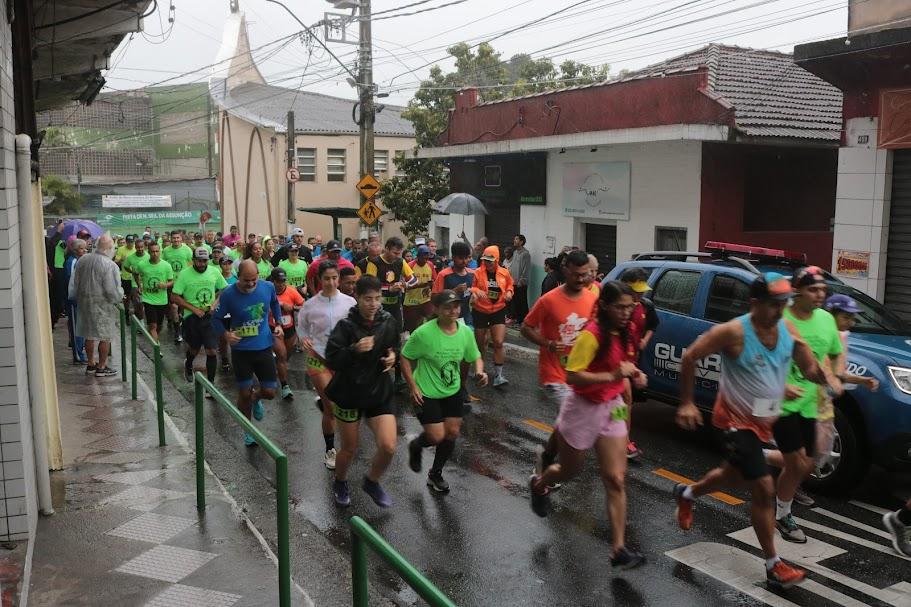 atletas correm em rua de subida. Uma viatura da guarda municipal acompanha. #paratodosverem 