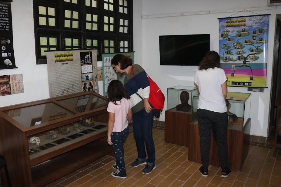 duas mulheres e uma criança observam artefatos da exposição #paratodosverem