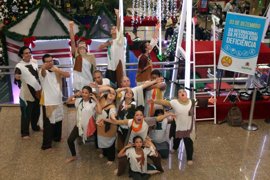 Jovens estão cantando e fazendo performance. Eles estão em meio a uma decoração de Natal. #Pracegover