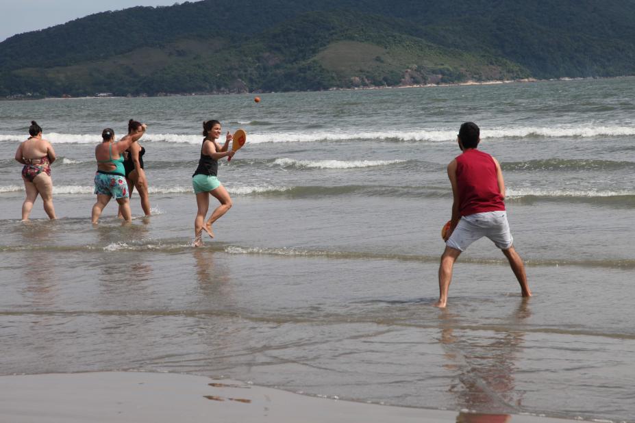 casal joga frescobol na praia #pracegover