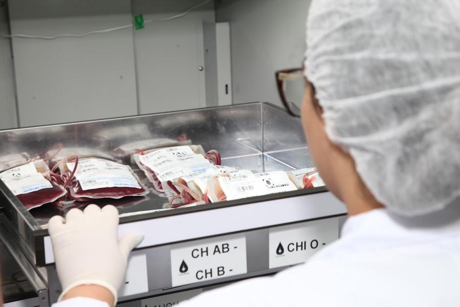 mulher está de costas segurando gaveta aberta com bolsas de sangue. #paratodosverem 