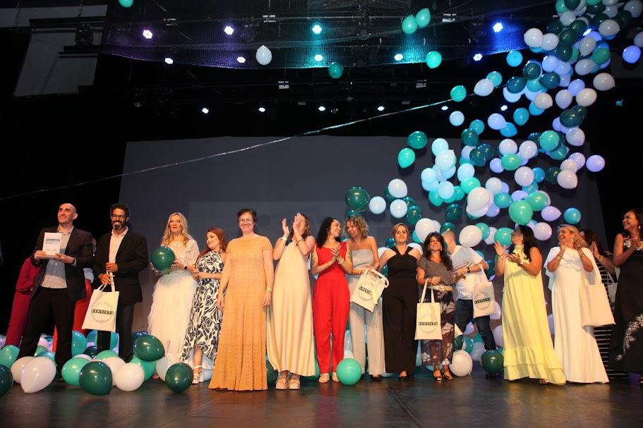 educadores premiados estão no palco. alguns aplaudem. Há balões de gás subindo. #paratodosverem 