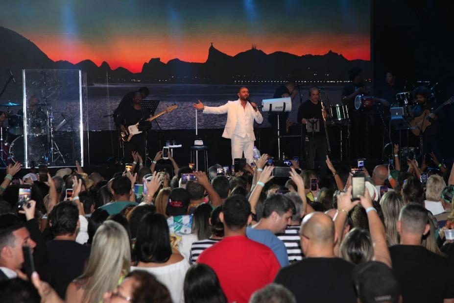 Diogo Nogueira no palco é fotografado pelo público na pista. #paratodosverem