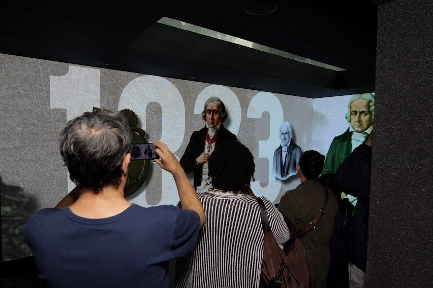 Munícipes tiram fotos de telões com imagens de José Bonifácio. #paratodosverem