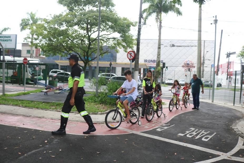 crianças de bicicleta seguem agente #paratodosverem