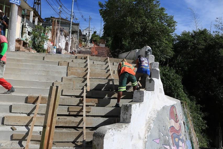 homens trabalham na construção de escadaria em morro. #paratodosverem