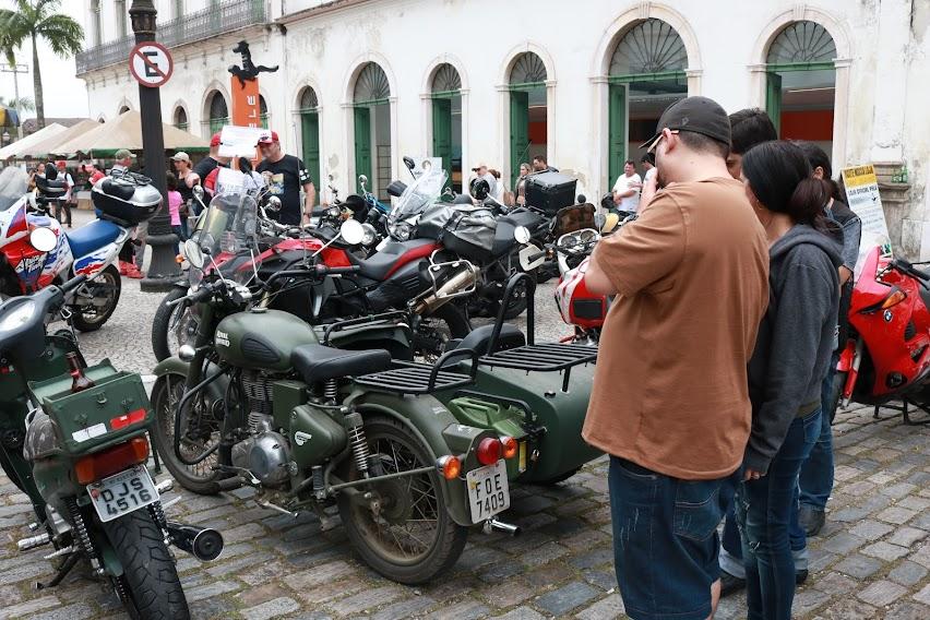 motos paradas em praça e várias pessoas olhando. #paratodosverem