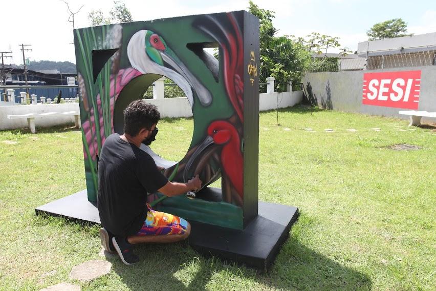 Artista grafita mureta já em finalização. Monumento tem uma grande ave. #paratodosverem