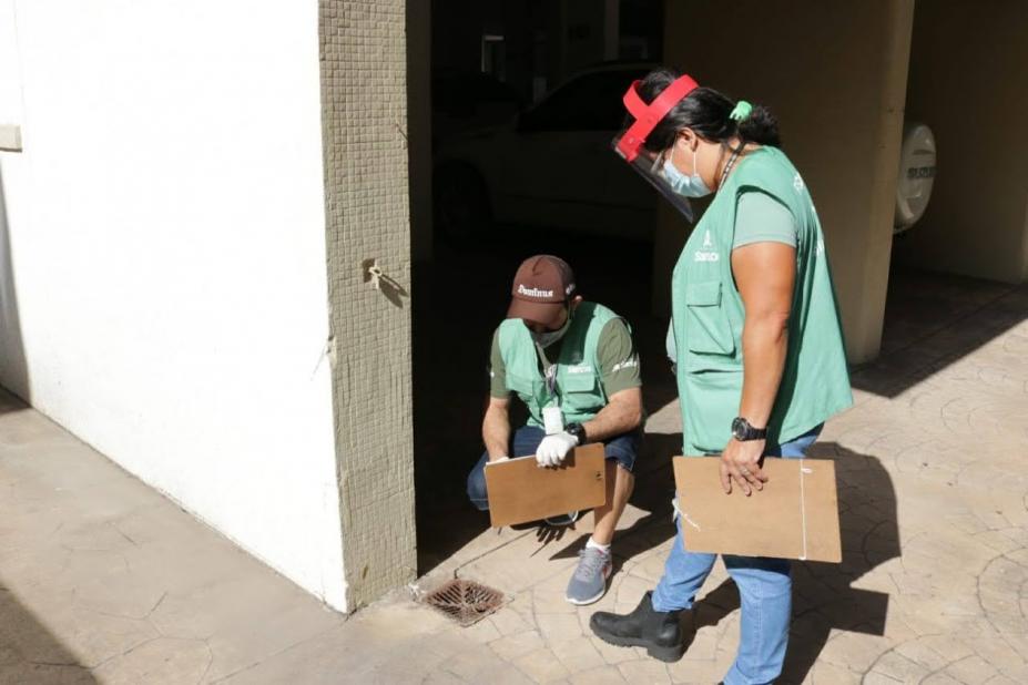 Par de agentes uniformizados examina ralo em imóvel. #Paratodosverem