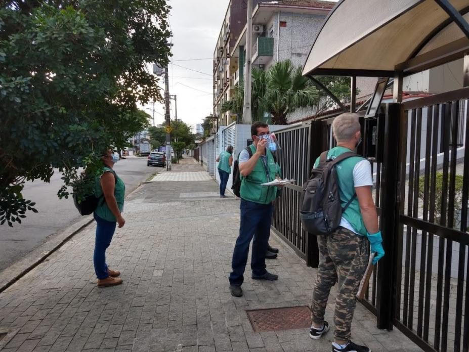 Agentes uniformizados estão na calçada, na entrada de um prédio. #Paratodosverem