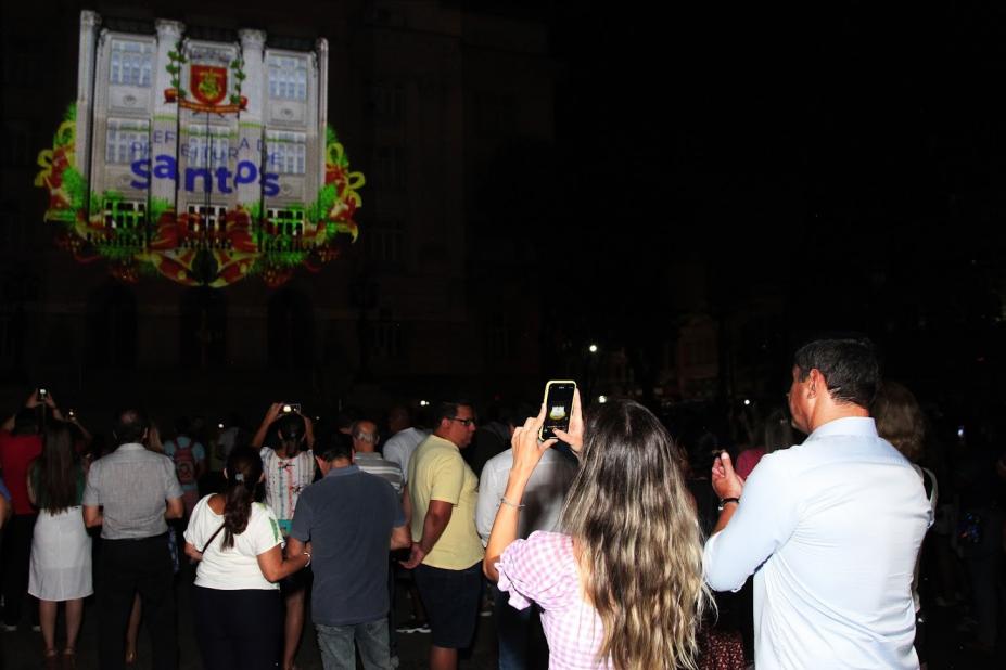 público assiste projeção mapeada no paço municipal. #paratodosverem