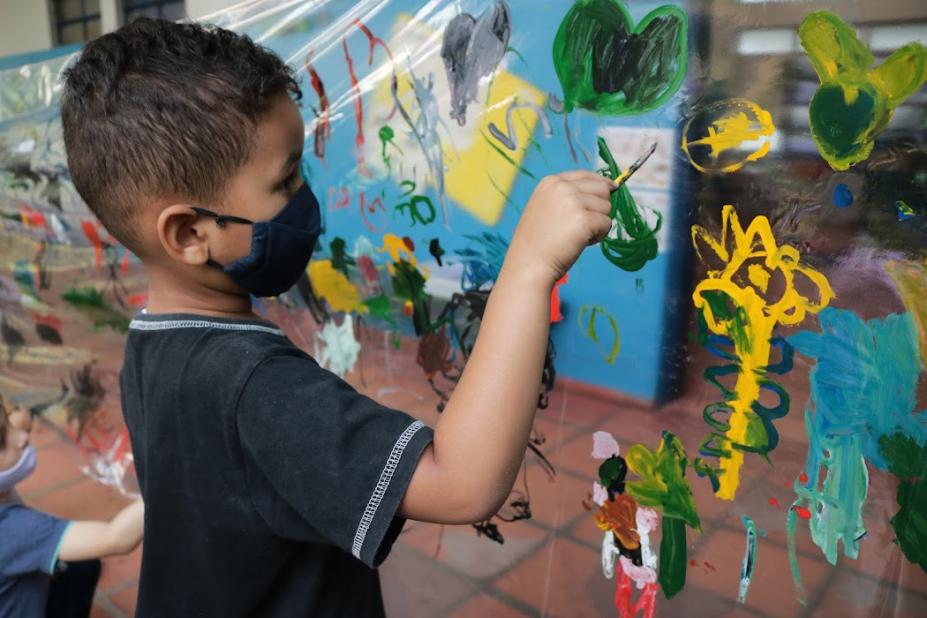 Criança pintando mural de plástico #paratodosverem