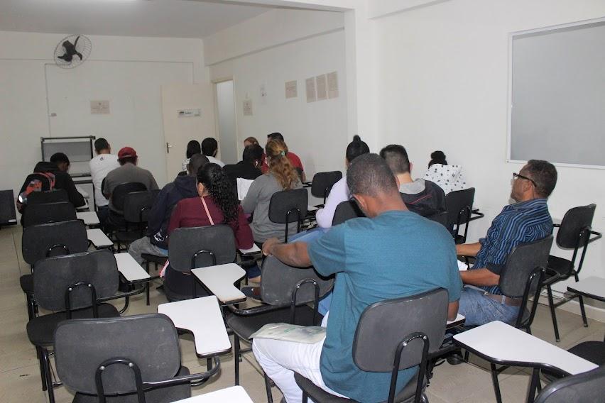 sala com vários candidatos sentados. Na imagem todos estão de costas. #paratodosverem