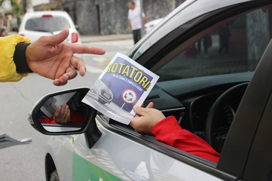 pessoa dentro do carro segura panfleto #paratodosverem