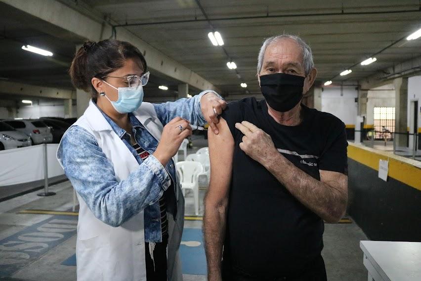 Mulher aplica vacina no braço de homem #paratodosverem