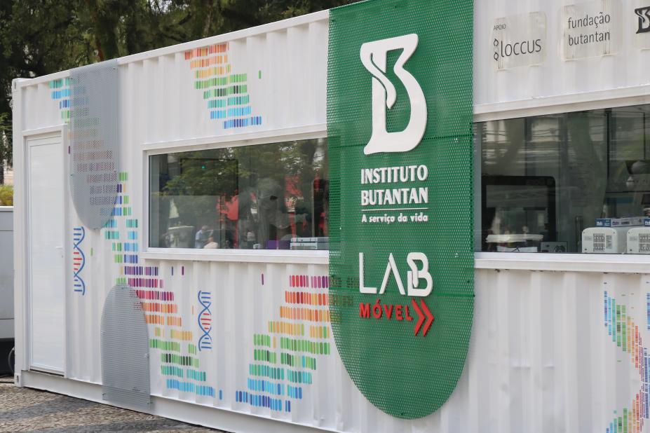 a fachada do labmóvel, com o logotipo do instituto butantan. O Labmóvel é um conteiner com parte fechada apenas por vidros, que permite ver o trabalho dos profissinais no interior. #paratodosverem