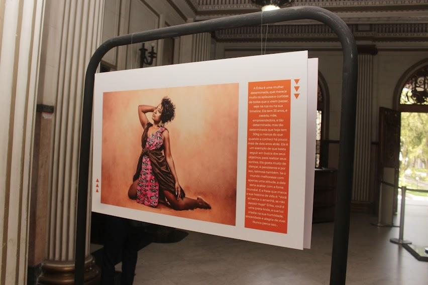 armação com foto pendurada. a imagem é de uma mulher negra em posição artística. ao lado da foto há um texto. #paratodosverem