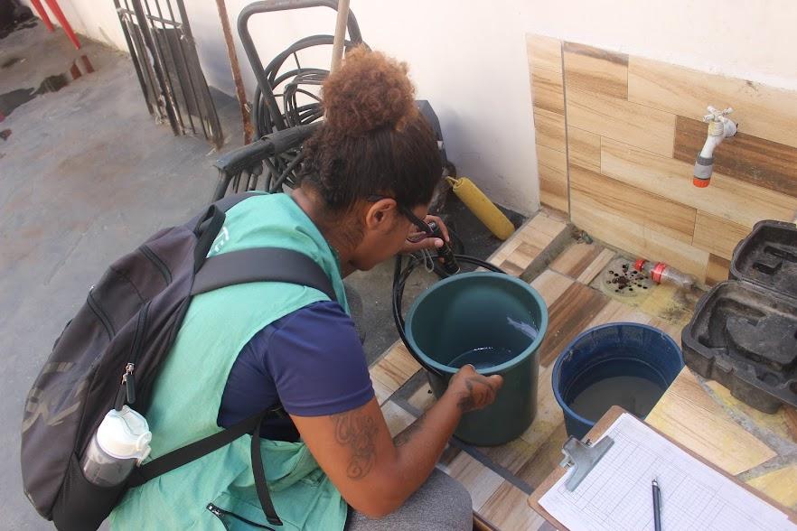 Agente vistoria interior de balde com água. #paratodosverem 