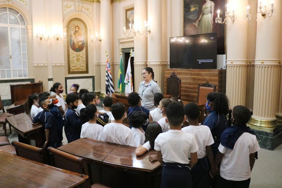alunos escutam guia dentro de sala histórica #paratodosverem