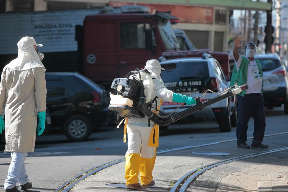 Homem com equipamento acoplado às costas pulveriza ambiente aberto. #Paratodosverem