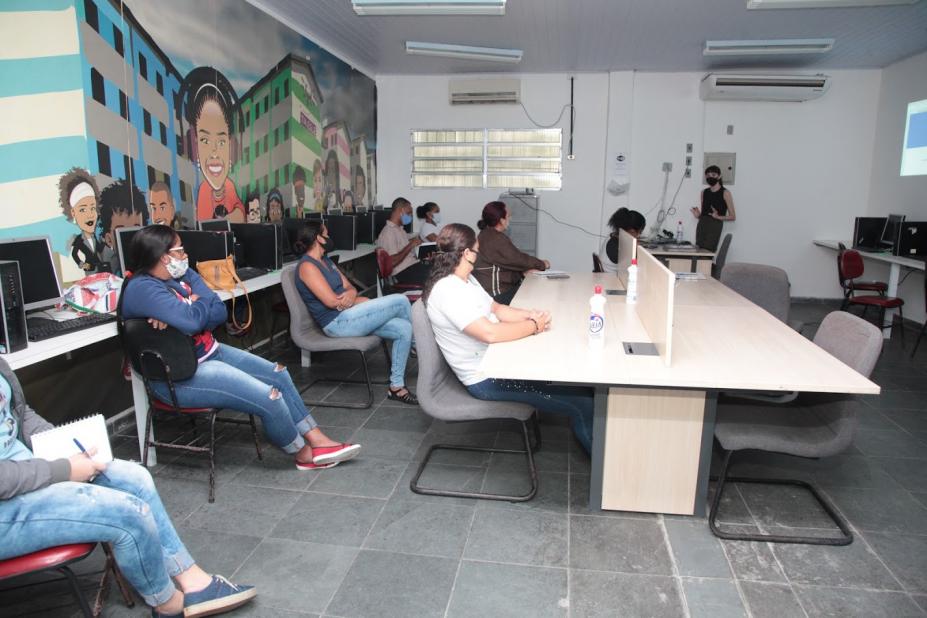 Várias pessoas sentadas em sala de aula assistindo palestra. #paratodosverem