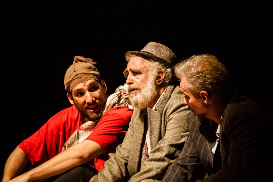 Homens sentados conversam em cena teatral #paratodosverem