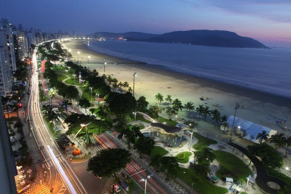 vista geral da avenida da orla à noite, em quase toda suas extensão, com as pistas iluminadas. #paratodosverem