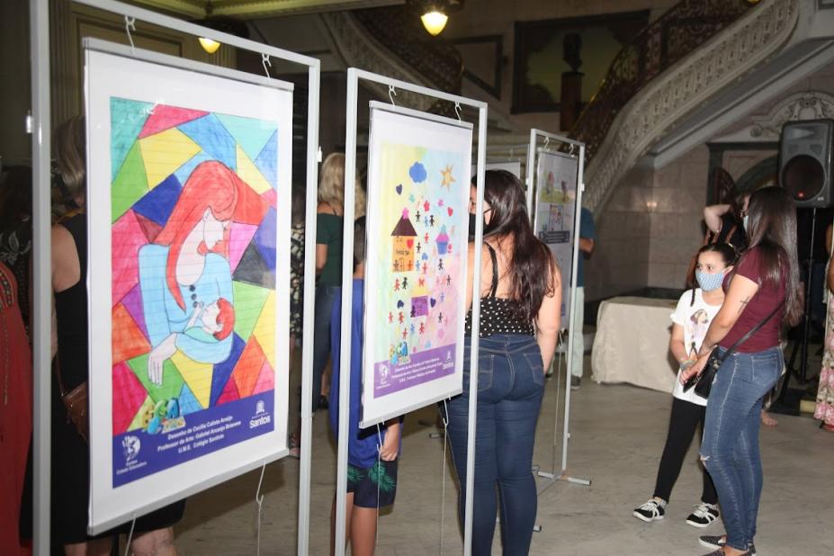 Pessoas olham para painéis com desenhos coloridos #paratodosverem