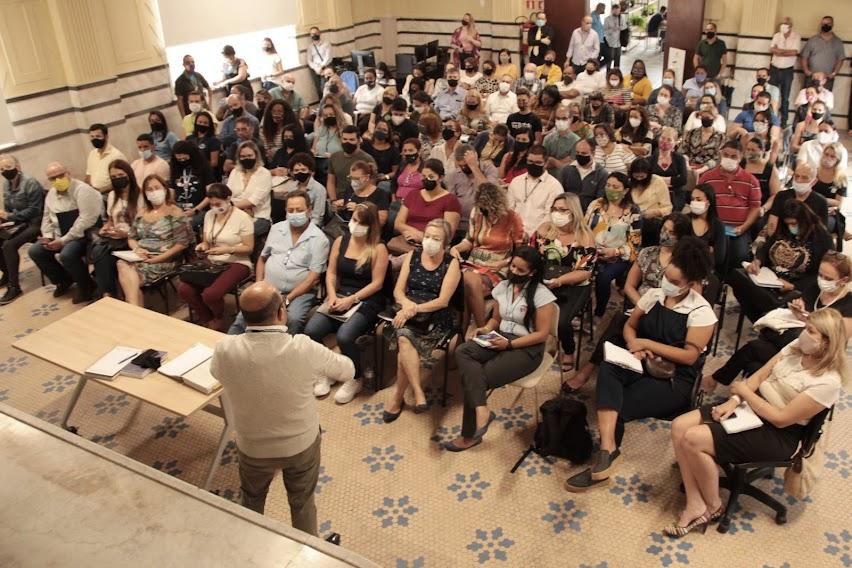 SALÃO CHEIO DE PESSOAS SENTADAS ASSISTINDO PALESTRA. #PARATODOSVEREM