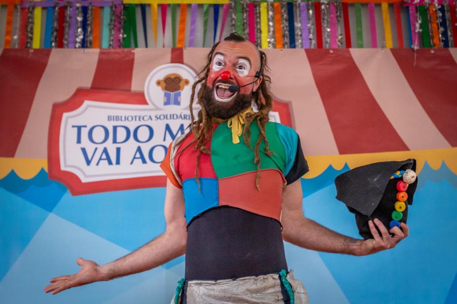 palhaço lixolino está sorrindo, com os braços abertos e segurando um chapéu na mão esquerda. #paratodosverem