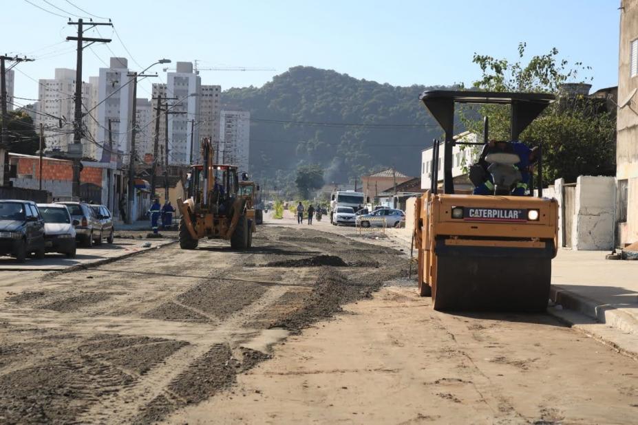 máquina compactadora percorre rua coberta de areia. #paratodosverem