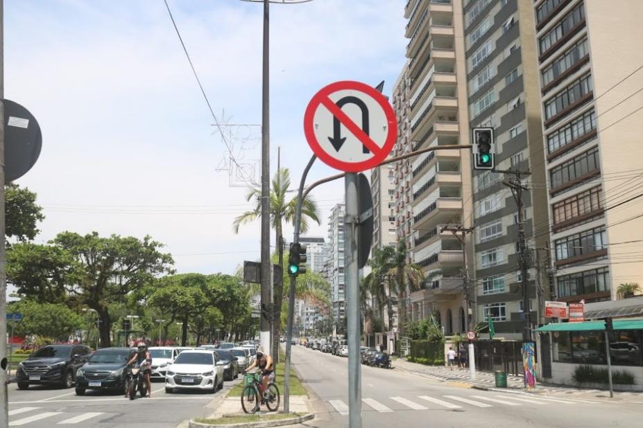 EM PRIMEIRO PLANO ESTÁ UMA PLACA PROIBINDO CONVERSÃO, COLOCADA EM CANTEIRO CENTRAL DA ORLA. áRVORES ESTÃO DO LADO ESQUERDO DA IMAGEM, E PRÉDIOS, À DIREITA. #PARATODOSVEREM