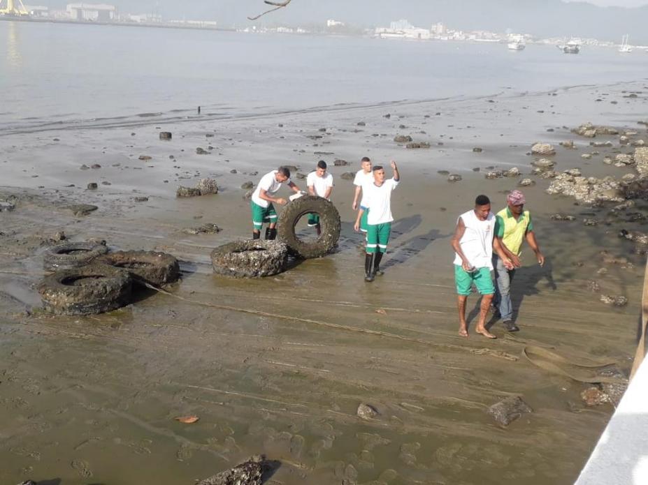 operários estão na faixa de areia mexendo e juntando pneus. #paratodosverem