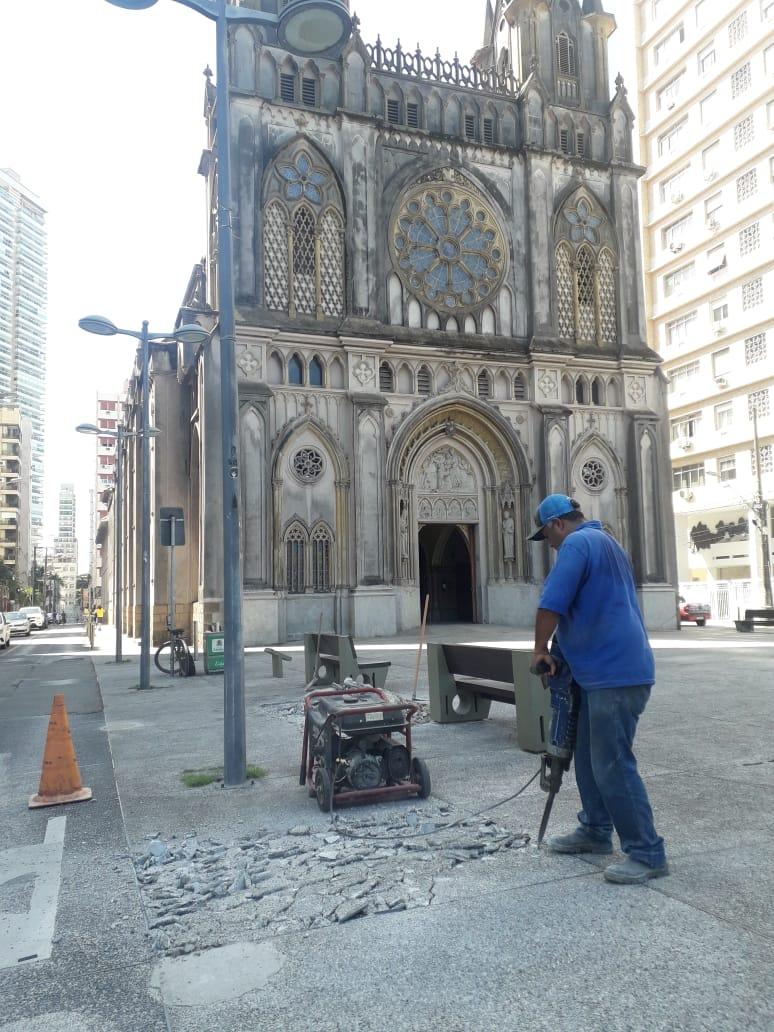 homem usa britadeira sobre piso diante de igreja. #paratodosverem