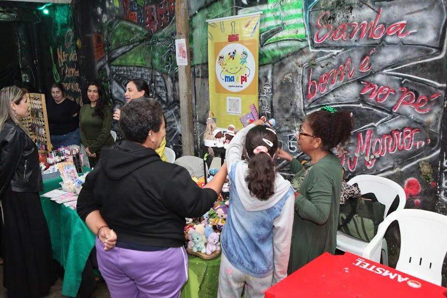 pessoas olhando artesanato em barraca #paratodosverem