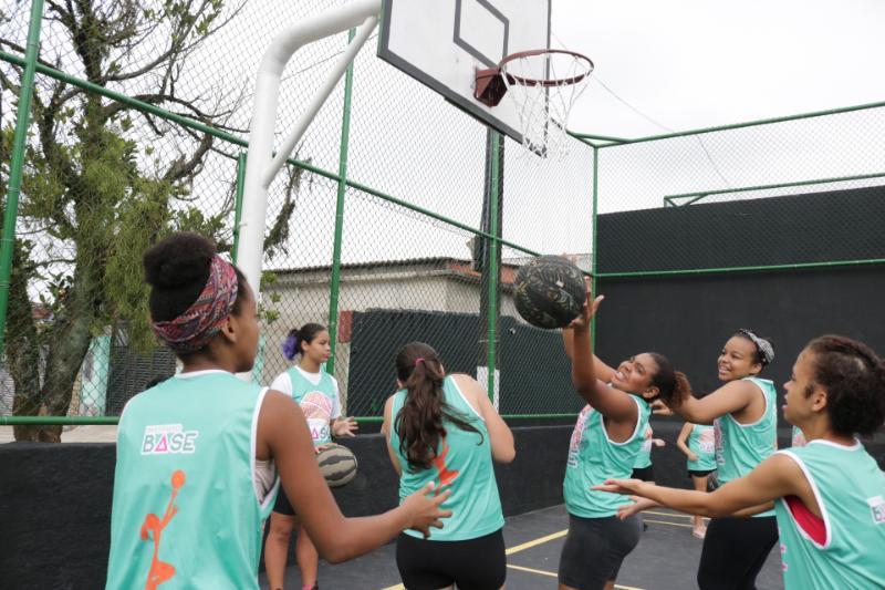 Meninas jogam basquete na quadra reformada. #pracegover