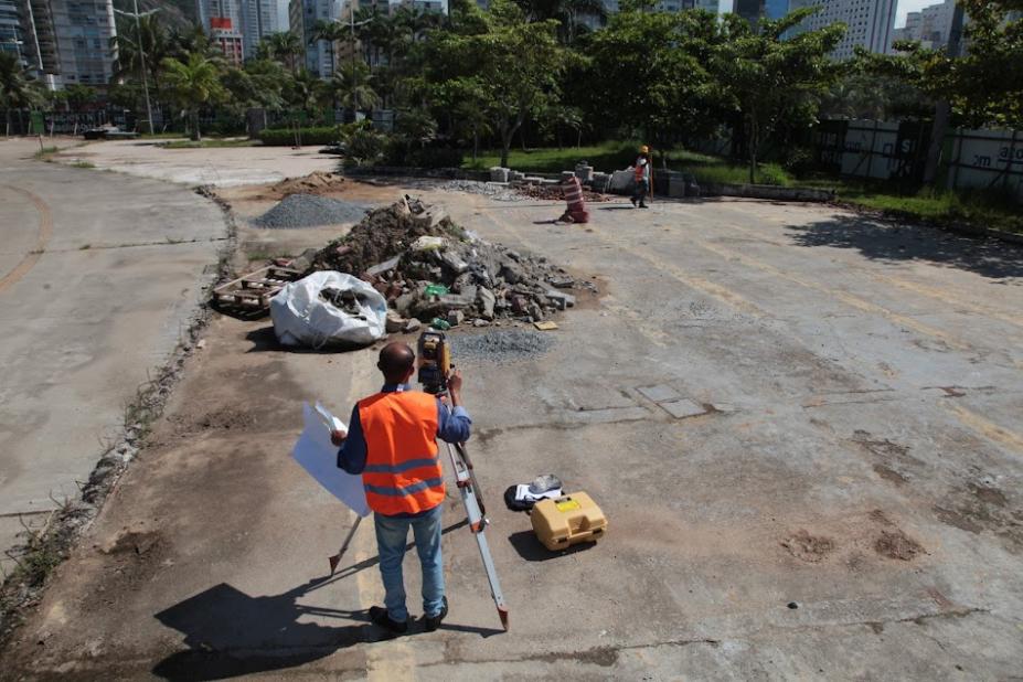 homemm uniformizado está atrás de equipamento de sondagem em terreno com piso quebrado. #paratodosverem