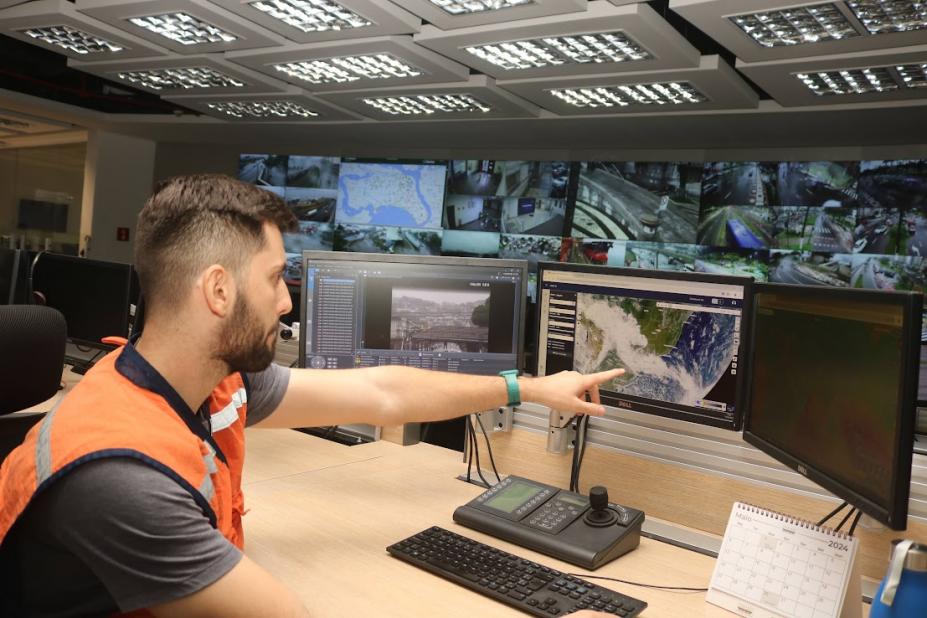 integrante da defesa civil aponta para tela de computador #paratodosverem 
