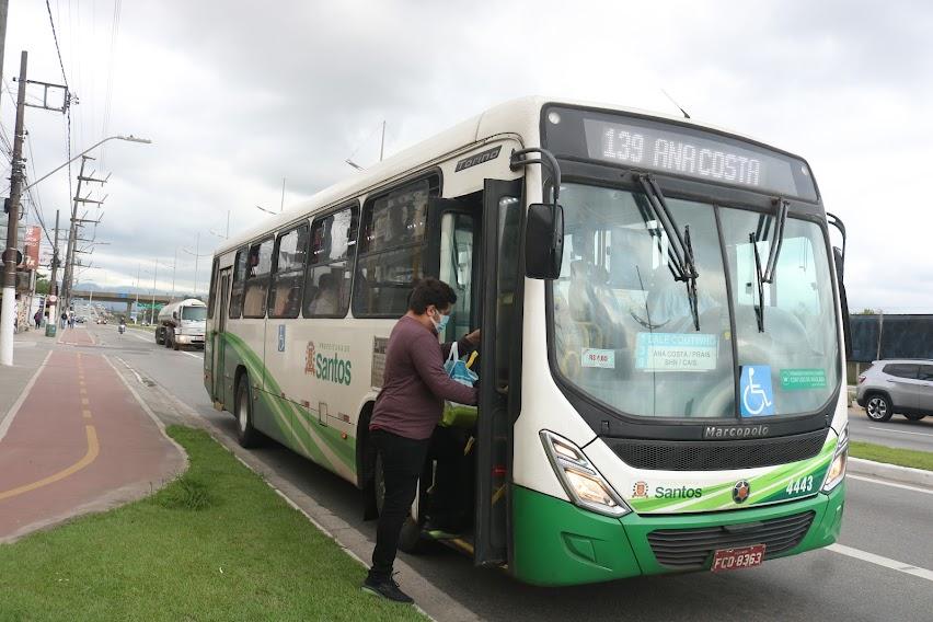 ônibus parada em via com pessoa subindo pela porta da frente. #paratodosverem