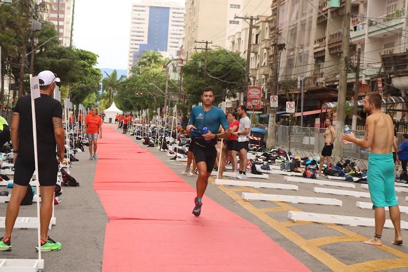 homem está correndo em rua sobre faixa vermelha. ao lado se vê grande estrutura esportiva, com bicicletas pelo chão.#paratodosverem 