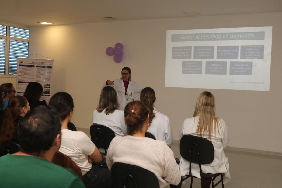 pessoas sentadas em auditorio assistem palestra. #paratodosverem 