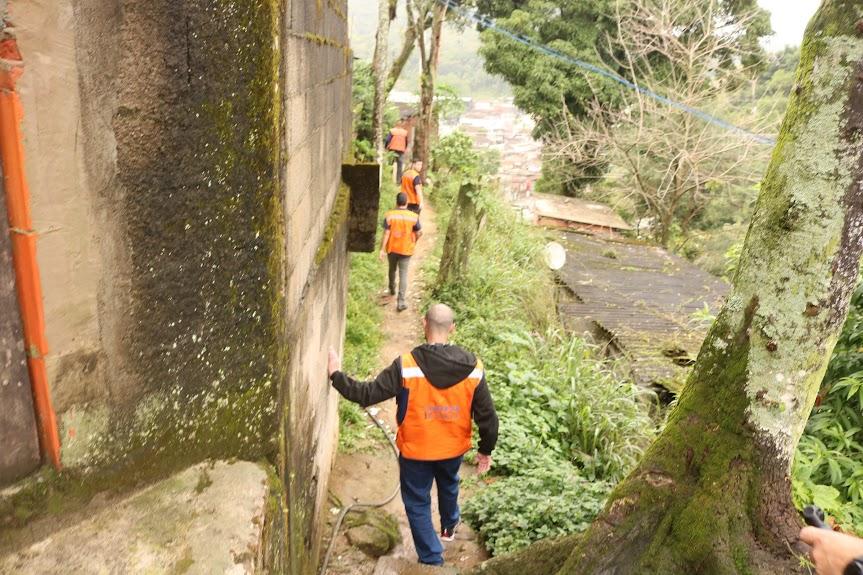 agentes da defesa civil caminham por rua de morro. #paratodosverem 