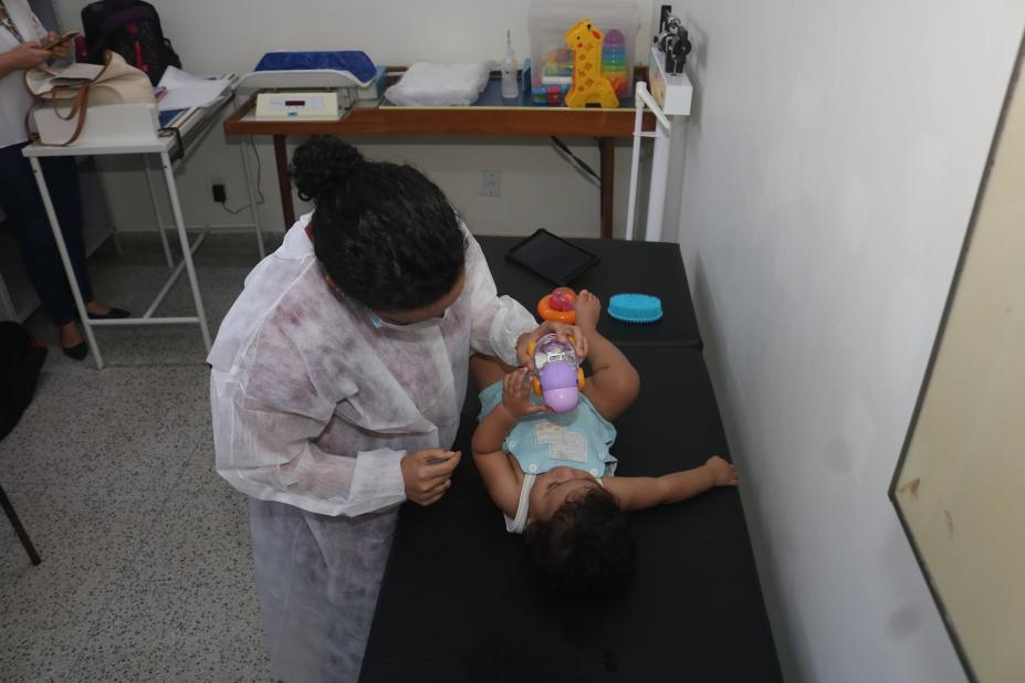 bebê é examinado em maca por mulher. #paratodosverem 