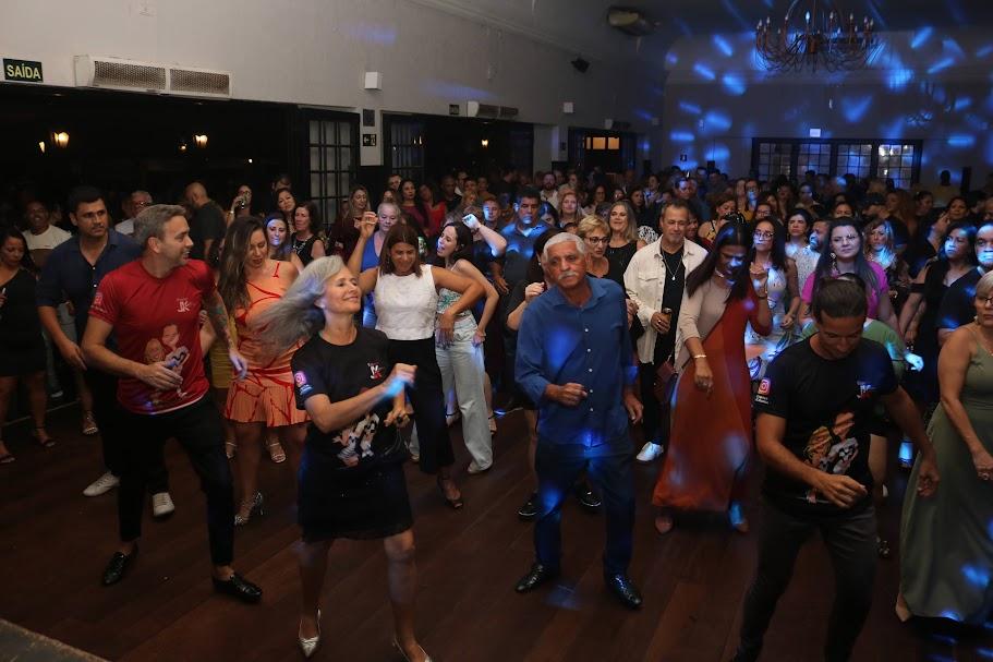 pessoas dançam em salão com iluminação especial de balada. #paratodosverem 