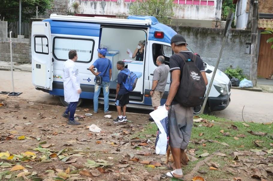 pessoas se aproximam de consultório montado em van estacionada na rua. #paratodosverem