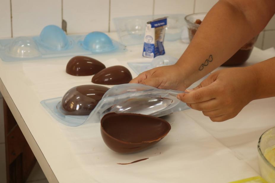 mãos desenformam ovo de chocolate. #paratodosverem 