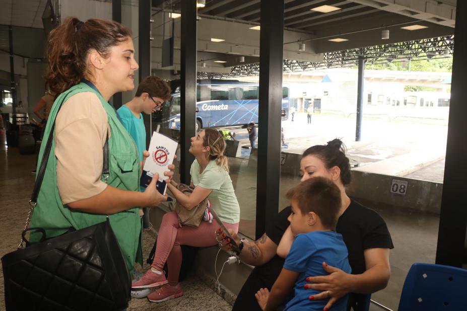 Imagem da agente orientando pessoas na Rodovária. #Paratodosverem.