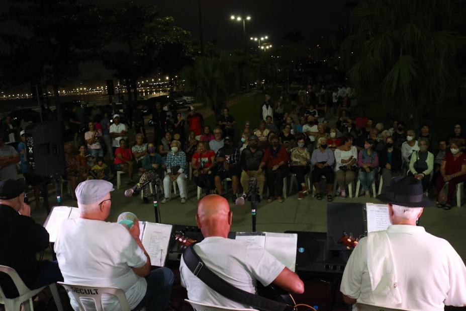 musicos tocam e plateia assiste sentada a noite em praça #paratodosverem